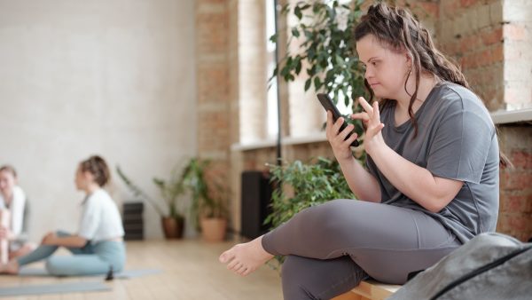 A woman with down's syndrome looks at her phone during a fitness class.